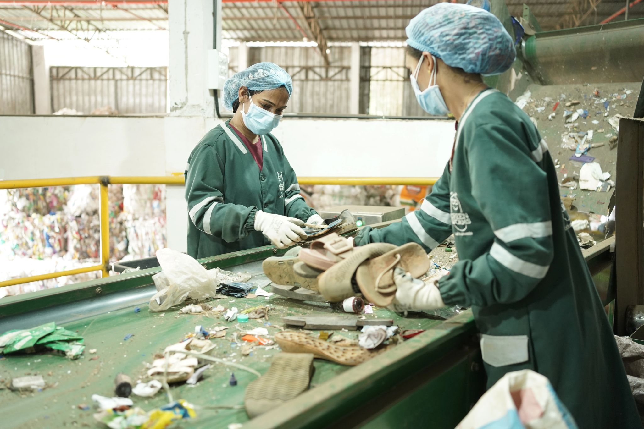 Team members processing footwear materials on conveyor belt